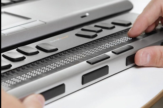 A braille device below a laptop keyboard.